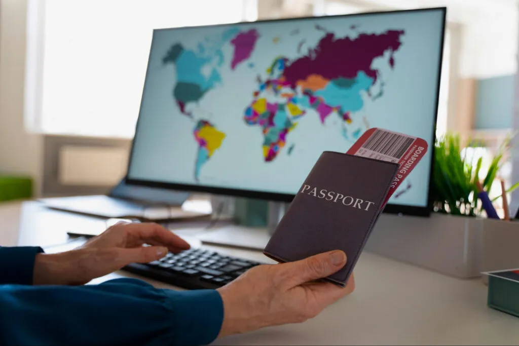 Uma pessoa com um computador e um passaporte à sua frente  